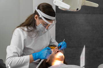 Dentist checks for violations in the natural bite after treatment with articulation paper....