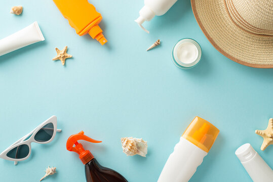 Create your summer oasis with these sun protection essentials: SPF cream and sunblock oil bottles, sunglasses, sunhat, shells, starfishes, on a pastel blue background with space for label and advert