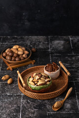 Various Nuts in wooden bowl on dark background.