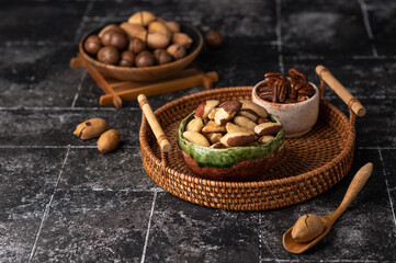 Various Nuts in wooden bowl on dark background.
