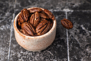 Pecan nuts on a rustic wooden table and pecan nuts in bowl.