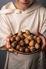 Boy holding a bowl with pecan and macadamia nuts. Healthy food and snack.