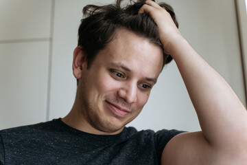 Surprised handsome young male holds head and looks with puzzlement aside, can't believe his eyes. High quality photo. High quality photo