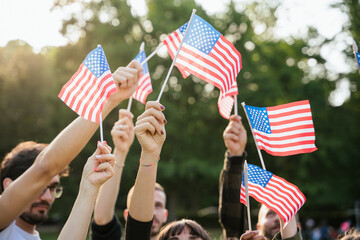 Group of people holds flags of the United States of America USA in the air celebrating citizenship at sunset outdoor - Copy space - 613475298