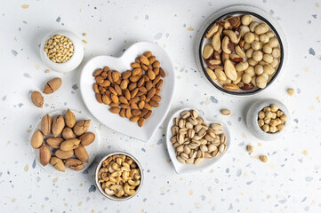Different types of nuts on a plate in the shape of a heart. Assorted nuts on a white background. Top view.