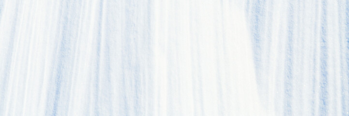 Beautiful winter background with snowy ground. Natural snow texture. Wind sculpted patterns on snow surface. Wide panoramic texture for background and design.