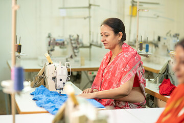 Indian woman working on sewing machine at textile factory.