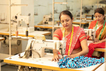 Indian woman working on sewing machine at textile factory.