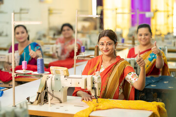 Indian women group showing thumbs up while work on sewing machine at textile factory.