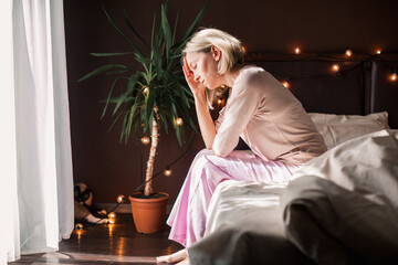 Unhappy sad middle aged woman sitting on bed at home - Powered by Adobe