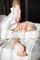 Senior woman stretching in bed waking up at home