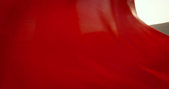 Ginger woman in red dress in field spins around her axis, like beautiful flower opening at spring dawn. Light movements of ginger woman and bright red colors of dress. Woman waving hem of her dress.