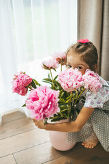 Girl hiding besides a big beautiful bouquet of pink peonies