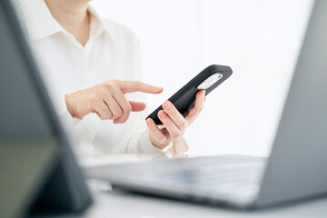 Side view shot of woman's hands using smart phone in interior, rear view of business man hands busy using cell phone at office desk, female officer typing on phone sitting at white table, flare