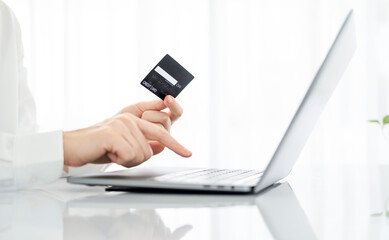 Woman hand holding credit card and using laptop at home, online shopping and paying bills, Payment method.