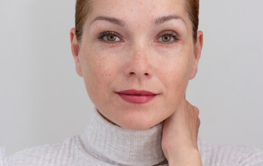 Portrait of cropped caucasian middle aged woman face with freckles on white background looking at...