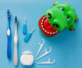 White dental floss, toothpicks, brushes and crocodile on blue