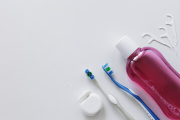 Top view of dental floss, toothbrushes, toothpicks and rinse on white background