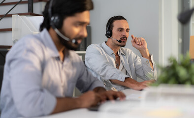Male customer service operator wear headset working in call center office to support people with telemarketing technology. Young man using headphone and microphone talking to client at helpdesk center