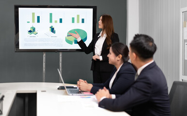 Businesswoman standing in conference room giving statistic presentation. Young Asian professional business woman talking, presenting strategy planning to executive working team in corporate meeting.
