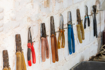Various colours used pliers hanging on wall in the workshop