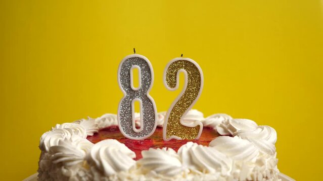 A candle in the form of the number 82, stuck in a holiday cake, is blown out. Celebrating a birthday or a landmark event. The climax of the celebration.