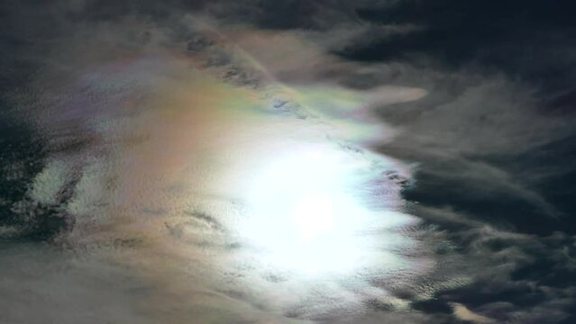 Natural blue sky background with colorful decorative clouds moving very slowly - Cloud iridescence, irisation around sun. Sunny autumn calm sky with colorful pearl colors - optical phenomenon in cloud
