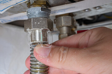 Gas leak at home boiler room. Inflating bubbles of soap mixture applied to the threaded joint on the gas flexible pipe indicate a gas leak. Preventing a gas explosion disaster.