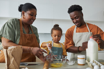 African American family baking together with their little daughter in the kitchen