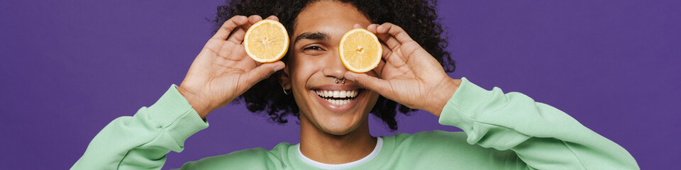 Young caribbean man smiling while making fun with lemon