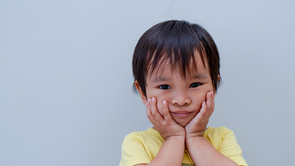 potrait of cute little asian boy holding his cheeks with his hands as suffering from toothache.