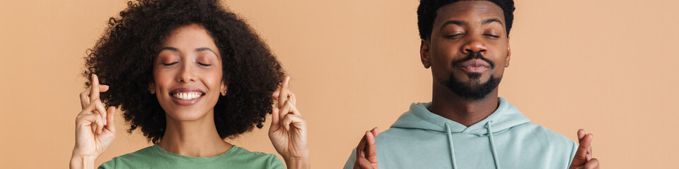 Black man and woman expressing happiness with fingers crossed