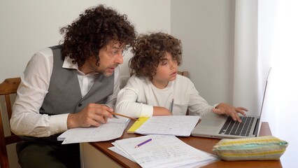 Fototapeta premium Father and son 9-year-old elementary school boy doing homework - doing school-given math exercises for the summer holidays - childhood lifestyle student with computer laptop 