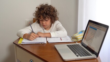 9-year-old elementary school boy doing homework - doing school-given math exercises for the summer...