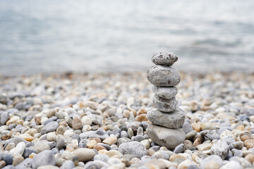 Fototapeta na wymiar Pyramid of pebbles on the sea beach.Waves in background