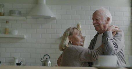 Slow motion of happy elderly couple dancing smiling laughing enjoying romantic relationship at home. Relationship and leisure time concept. - Powered by Adobe