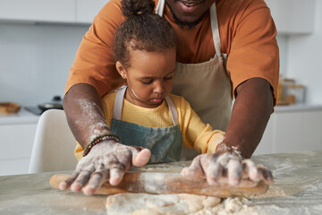 African American dad teaching his daughter to bake, they rolling dough with rolling pin together