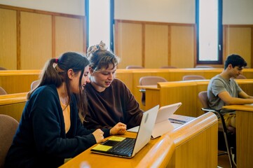 Obraz premium Team of woman students sitting at desk with laptop and tablet