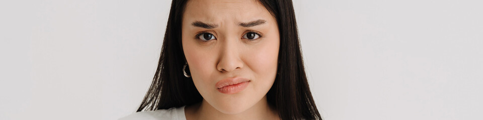 Obraz premium Asian puzzled woman gesturing while using mobile phone