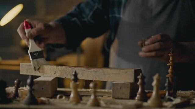 Blackboard, Medium-sized business owners Concentrated Holds a paintbrush works with wood In the workshop Close-up Beginner repairman Is at the workplace at the table In the workshop, carpentry