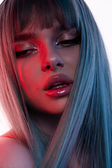 High fashion model face woman in colorful bright neon UV blue and red lights, posing in studio, beautiful girl, glowing makeup, colorful makeup. Glitter Bright Neon Makeup
