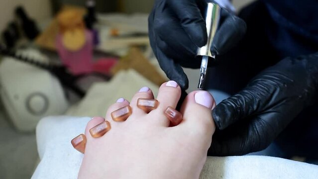 Professional pedicure master polishing nails with glitter top shellac , horizontal  4k footage