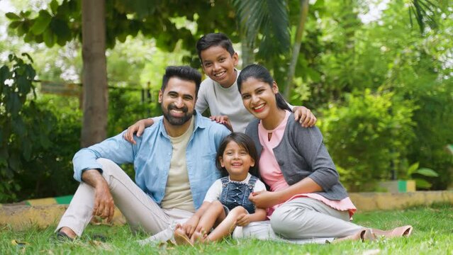 Happy indian family with sbling kids spending time together at park - concept of weekend holidays, family time and parenthood