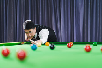 Fototapeta premium Asian young man aiming snooker ball with professiona