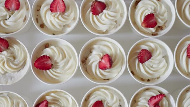 Circular motion of dessert cups, whipped cream strawberries nut pieces