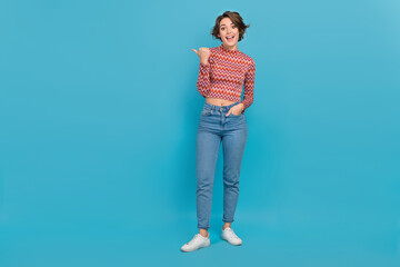 Fototapeta na wymiar Full length photo of cool excited woman dressed print top pointing thumb empty space isolated blue color background