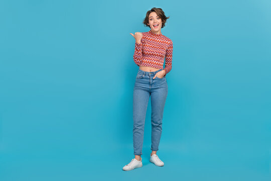 Full length photo of cool excited woman dressed print top pointing thumb empty space isolated blue color background