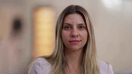 Close-up face of a woman in her 30s looking at camera with neutral expression