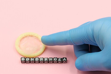 Doctor's hand pointing to a condom. Combating sexually transmitted diseases - obrazy, fototapety, plakaty