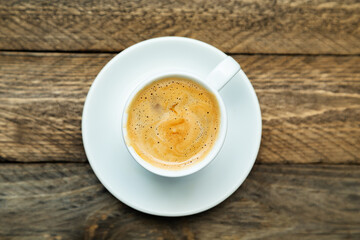 Cup of freshly brewed coffee on a wooden background.